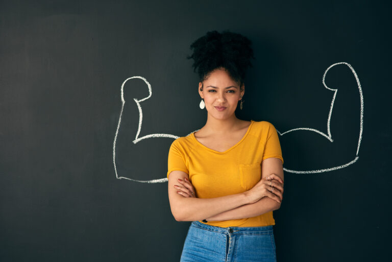 Shot of a woman posing with a chalk illustration of flexing muscles against a dark background.